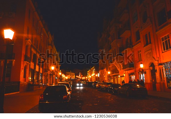 Kyiv City center, Night Street\
with cars along the road and yellow lights under dark blue\
sky