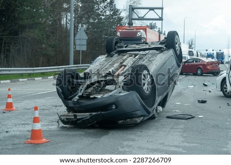 Kyiv region, Ukraine - April 10, 2023: Overturned car on the highway during the approach to the city. Traffic accident on the autobahn. Crashed and overturned cars on the highway. 