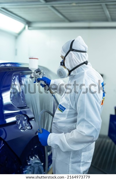 Kyiv, Ukraine - 02.02.2022: man painting blue car\
in spray booth