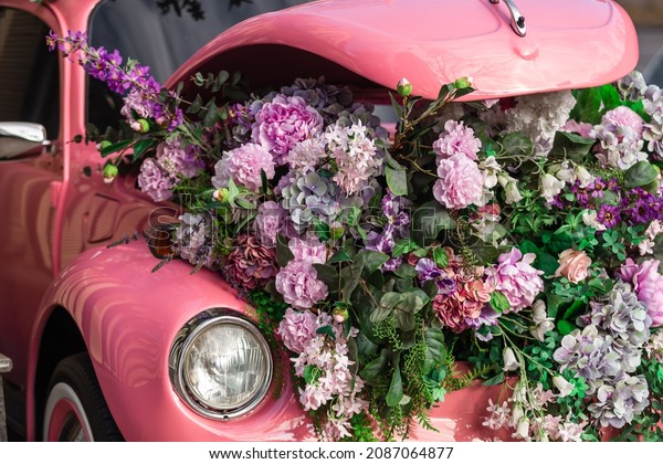 Kyiv, Ukraine -\
11.16.2021 vehicle  alternative energy or Eco concepts. A retro car\
covered flowers. Pink vehicle decorative with many flowers, flower\
and bouquet delivery.