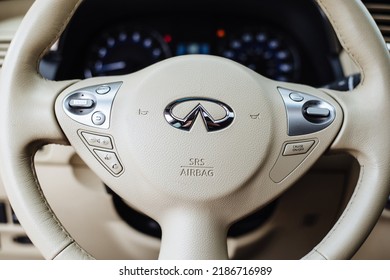 Kyiv, Ukraine - 20.05. 2020: Infiniti Metal Logo Close-up. Japanese Car Manufacturer. It Is A Mazda Brand Used For Luxury Cars. The Steering Wheel Of A Business Class Car Is Made Of White Leather