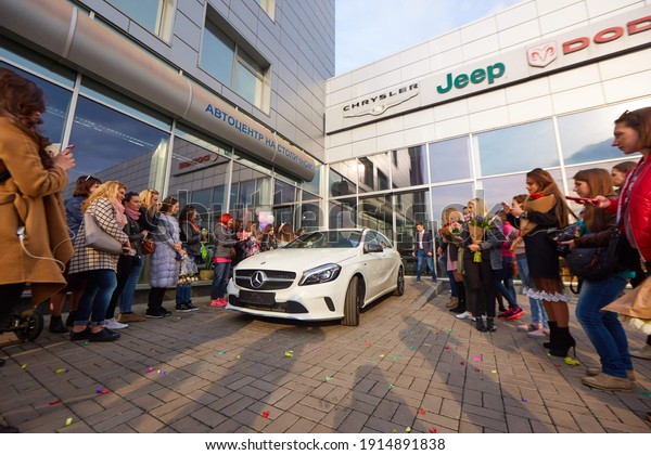 Kyiv,\
Ukraine - 27.03.2017: many friends congratulate a beautiful girl on\
the purchase of a Mercedes in a car\
dealership