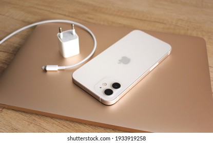 Kyiv, Ukraine — 5 March 2021: The new Apple iPhone 12 with 5G next and magsafe support, located on a MacBook laptop next to a charger that is not included. Fight for the environment. Carbon footprint.