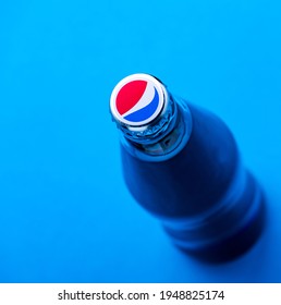 Kyiv, Ukraine - April 2, 2020: Cap with the logo of the American brand Pepsi. Glass bottle 0.25 l stands on a blue background top view. Close up.