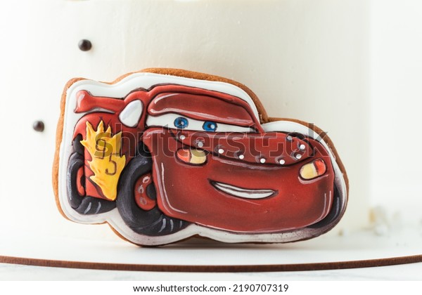KYIV, UKRAINE\
- August 01: Birthday cake with gingerbread cookie in the shape of\
Lightning McQueen Car character of animated Pixar film series.\
White cake with red edible race\
car