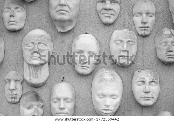 Kyiv,\
Ukraine - August 1, 2020: The wall with faces. Wall with face masks\
chaotically arranged. There are different faces, male and female,\
old and young, similar to post-mortem gypsum\
masks.