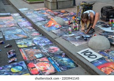 KYIV, UKRAINE - AUGUST 23, 2022: Girl Street Artist Paints With A Spray Can Of Paint On Paper On A City Street