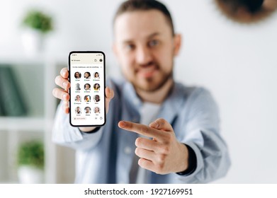 Kyiv, Ukraine - February 28, 2021. Defocused Modern Guy Holds A Cellphone With The Clubhouse App On The Screen, And Points Finger At It. App For Audio Communication, Of Diverse People Around The World