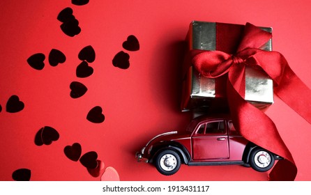 Kyiv, Ukraine - Febuary 10, 2021: Gift On The Roof Of A Red Car On A Red Background. February 14 Card, Valentine's Day. Flower Delivery. 8 March, International Happy Women's , Christmas