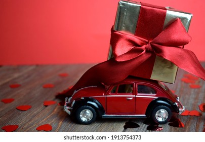 Kyiv, Ukraine - Febuary 10, 2021: Gift On The Roof Of A Red Car On A Red Background. February 14 Card, Valentine's Day. Flower Delivery. 8 March, International Happy Women's , Christmas