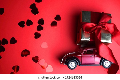 Kyiv, Ukraine - Febuary 10, 2021: Gift On The Roof Of A Red Car On A Red Background. February 14 Card, Valentine's Day. Flower Delivery. 8 March, International Happy Women's , Christmas