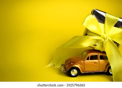 Kyiv, Ukraine - Febuary 27, 2021: Gift On The Roof Of A Gold Car On A Yellow Background. February 14 Card, Valentine's Day. Flower Delivery. 8 March, International Happy Women's , Christmas