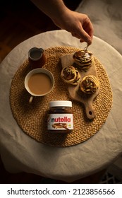 KYIV, UKRAINE - JANUARY 1, 2022:  Pancakes Smeared With Nutella Top View. Jar Of Nutella And Mini Pancakes