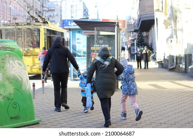 Kyiv, Ukraine - January 2 2022: Parents With Two Kids Running To Catch A Trolley Bus Waiting At The Stop