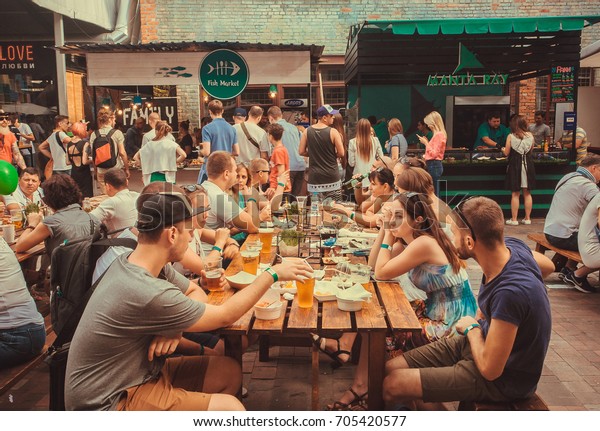 KYIV, UKRAINE - JUL\
23: Friendly party with crowd of  people eating at table during\
outdoor Street Food Festival on July 23, 2016. Kiev is the 8th most\
populous city in Europe.