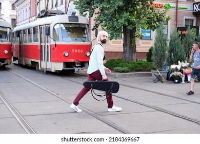 Kyiv, Ukraine - July 29 2022: man with a violin case walking the street across tramway tracks