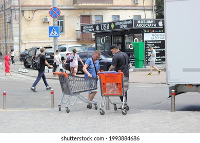 Kyiv, Ukraine - June 18 2021: Two Men With Empty Shopping Carts Standing On Curb Near Cargo Delivery Truck