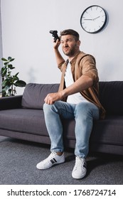 KYIV, UKRAINE - JUNE 9, 2020: Angry Man Throwing Joystick While Sitting On Sofa At Home