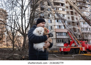 KYIV, UKRAINE - Mar. 15, 2022: War in Ukraine. A man and his dogs stand in front of a badly damaged residential building that was hit by a Russian shell.