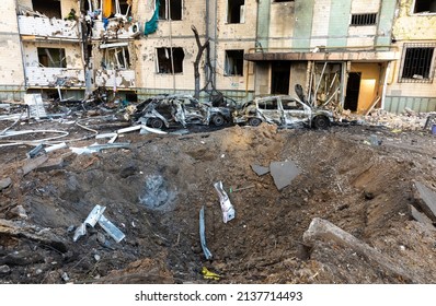 KYIV, UKRAINE - Mar. 20, 2022: War in Ukraine. Еxplosive funnel, residential building and cars damaged by falling debris after Russian rocket attack on Kyiv.