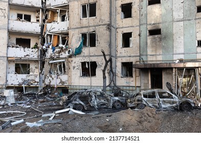 KYIV, UKRAINE - Mar. 20, 2022: War in Ukraine. Ð•xplosive funnel, residential building and cars damaged by falling debris after Russian rocket attack on Kyiv.