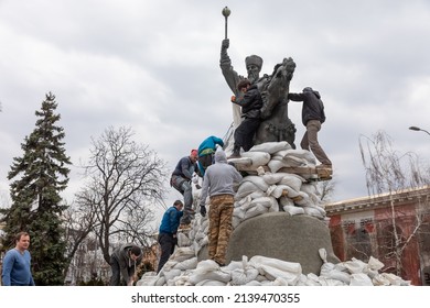 KYIV, UKRAINE - Mar. 26, 2022: War in Ukraine. Monument to Hetman Sahaidachny with sandbags to protect against Russian shelling in Kyiv. A group of young people cover the monument with sandbags