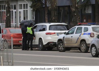 Kyiv Ukraine - March 05 2021: Two Police Officers Stopped The Intruder's Car On A Busy City Street. Police Officers Monitor Drivers In Traffic. Checking The Driver's Documents. Street Photography.