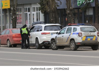 Kyiv Ukraine - March 05 2021: Two Police Officers Stopped The Intruder's Car On A Busy City Street. Police Officers Monitor Drivers In Traffic. Checking The Driver's Documents. Street Photography.