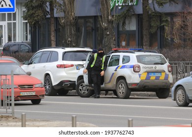 Kyiv Ukraine - March 05 2021: Two Police Officers Stopped The Intruder's Car On A Busy City Street. Police Officers Monitor Drivers In Traffic. Checking The Driver's Documents. Street Photography.