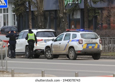 Kyiv Ukraine - March 05 2021: Two Police Officers Stopped The Intruder's Car On A Busy City Street. Police Officers Monitor Drivers In Traffic. Checking The Driver's Documents. Street Photography.