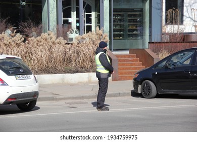 Kyiv, Ukraine - March 11 2021: Parking Lot Attendant Standing On A Road Curb