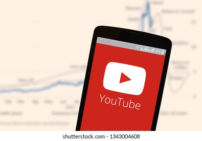 KYIV, UKRAINE - MARCH 19, 2019: The image of the logo of Youtube in the phone screen on the background of graphics