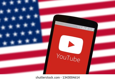 KYIV, UKRAINE - MARCH 19, 2019: The image of the logo of Youtube in the phone screenon the background of the flag of USA