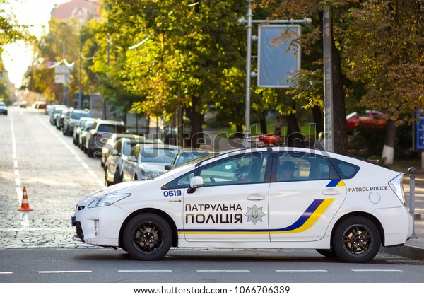 KYIV, UKRAINE - March 30,\
2018: Ukrainian white police car cruiser with emergency lights\
driving along city street in the evening. Security and control in\
modern life.
