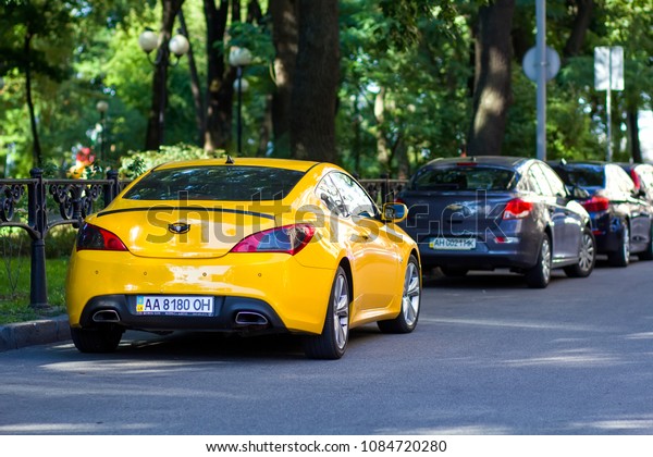 KYIV, UKRAINE - March 30, 2018: Long row of cars\
parking along a city road under shadow of big trees on bright\
summer day. Transportation, parking problems and technology\
concept.