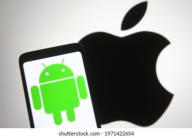 
KYIV, UKRAINE - MAY 10, 2021: In this photo illustration Android logo is seen on a mobile phone screen in front of Apple logo in the background.