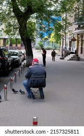 Kyiv, Ukraine - May 17 2022: Man Sitting In A Small Chair On A Sidewalk