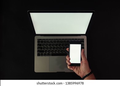 Kyiv, Ukraine - May 1st 2019: Mockup, MacBook Pro Isolated On Black Background With Man's Hands Holding Iphone 7