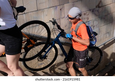 Kyiv, Ukraine - May 29 2022: Cyclist Going Up The Steps Of Stairs Of Underground Passage And Carrying His Bicycle