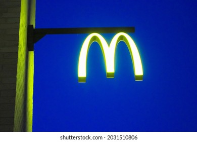 Kyiv, Ukraine. May 4, 2021. McDonald's sign against a blue evening sky. Luminous yellow golden arch logo of a brand in a form of letter M against a night skyline. American fast food restaurant cafe.