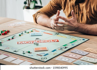 KYIV, UKRAINE - NOVEMBER 15, 2019: Cropped View Of Man Sitting At Table With Monopoly Game