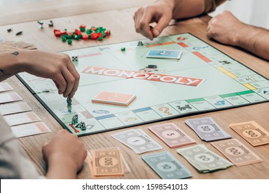 KYIV, UKRAINE - NOVEMBER 15, 2019: Cropped View Of Man And Women Playing Monopoly Game At Table