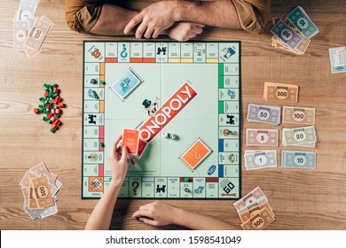 KYIV, UKRAINE - NOVEMBER 15, 2019: Cropped View Of Woman Holding Cards While Playing With Man In Monopoly At Table