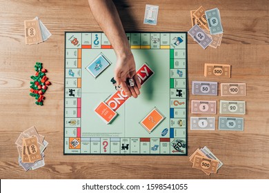 KYIV, UKRAINE - NOVEMBER 15, 2019: Cropped View Of Man Holding Dices With Monopoly Game On Table