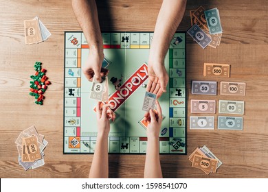 KYIV, UKRAINE - NOVEMBER 15, 2019: Cropped View Of Man And Woman Playing Monopoly Game At Table