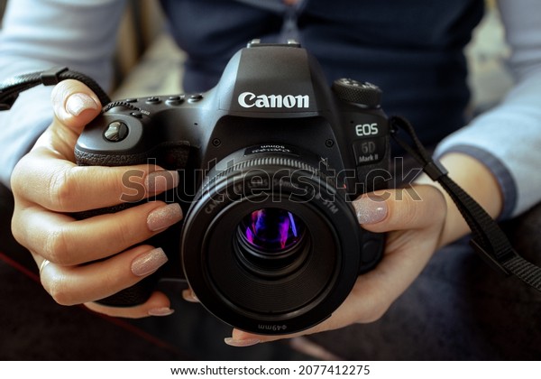 KYIV, UKRAINE - NOVEMBER 6, 2021: Canon 6D Mark II\
camera in female hands. A woman photographer is holding a Canon\
camera in her hands