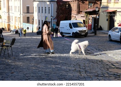 Kyiv, Ukraine - October 15 2022: Woman Walking Big White Dog, Dog Pulling The Leash