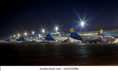 Kyiv, Ukraine - October 18, 2019: Night Airport Borispol. Aircraft UR-PSR Of Ukrainian National Airlines Are On The Runway. The Lights Of The Airfield. Night Life Of The Platform And Terminal. 