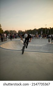 Kyiv, Ukraine - September 12, 2021: Extreme Cyclist Performs Tricks In The Skate Park. Extreme Sport. Crowded Skatepark. A Group Of Guys Show Tricks On The Ramp. BMX Tricks.