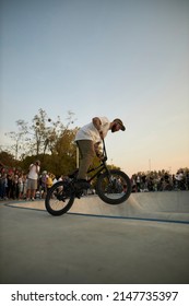 Kyiv, Ukraine - September 12, 2021: Extreme Cyclist Performs Tricks In The Skate Park. Extreme Sport. Crowded Skatepark. A Group Of Guys Show Tricks On The Ramp. BMX Tricks.